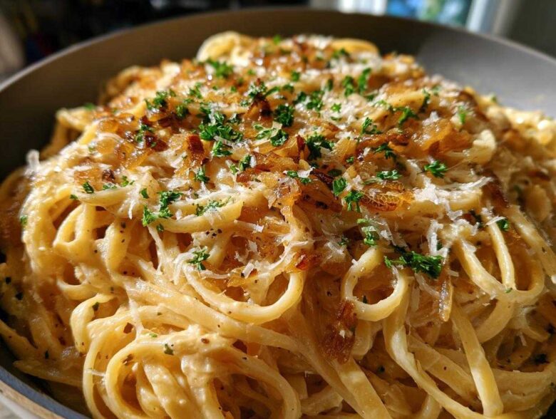 Close-up of creamy french onion pasta tossed in sauce, topped with caramelized onions, grated cheese, and fresh parsley.