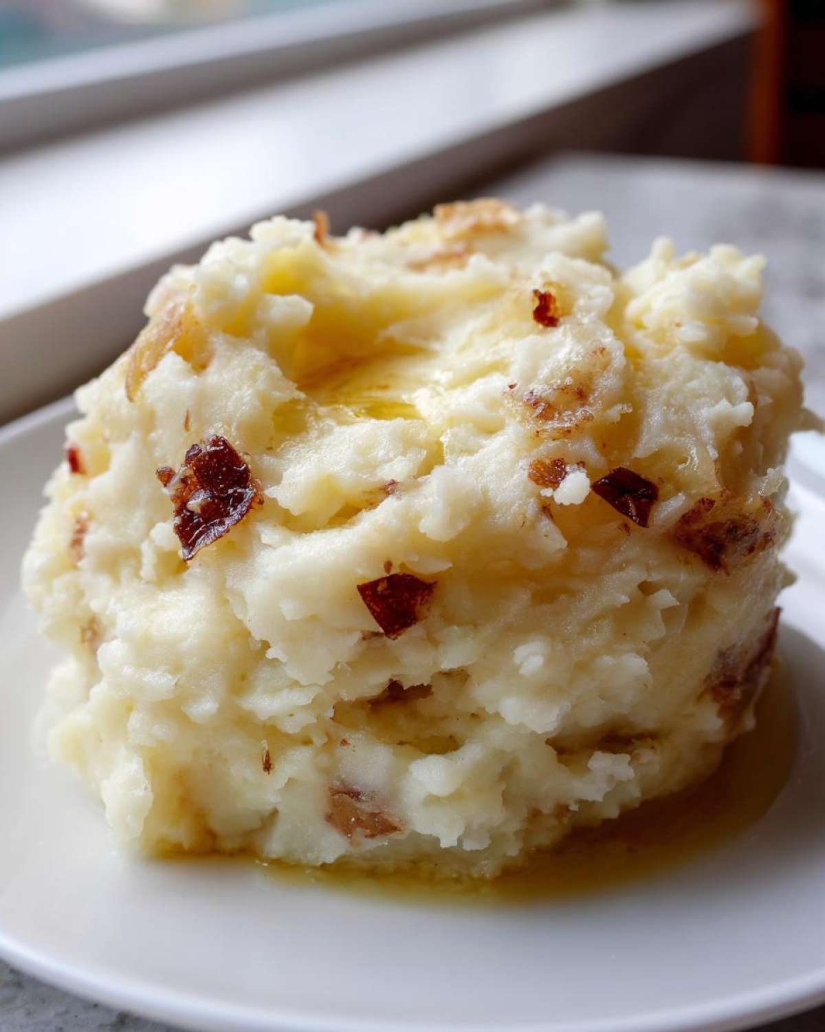 A scoop of creamy garlic mashed potatoes topped with melted butter and crispy bits.