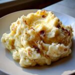 A close-up of creamy garlic mashed potatoes topped with melted butter and crispy bits.