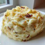 A mound of creamy garlic mashed potatoes topped with crispy browned bits, served on a white plate.