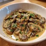 A close-up of sliced mushrooms coated in a rich, creamy mushroom sauce and garnished with fresh parsley.