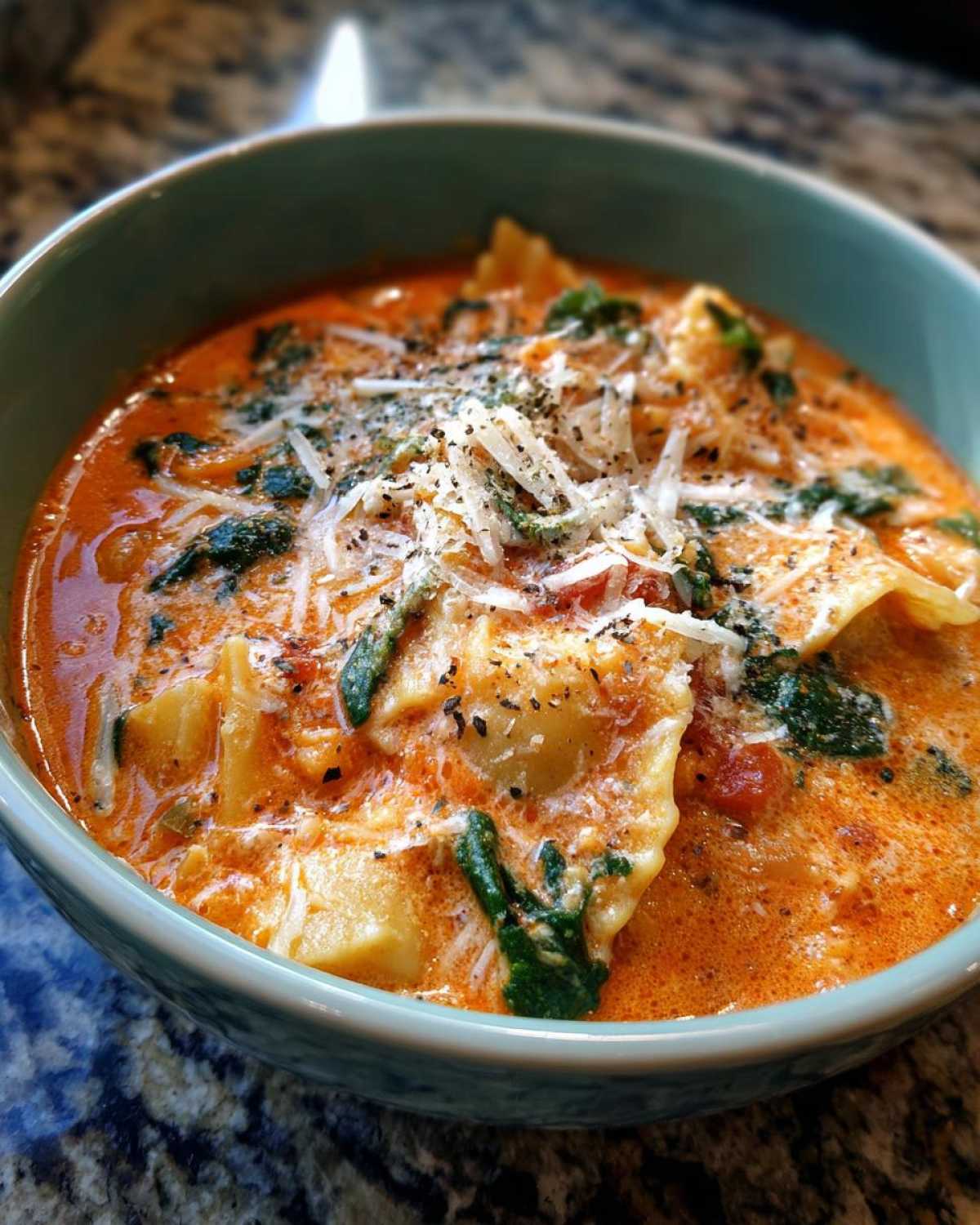 Close-up of a bowl of rich, creamy one pot lasagna soup garnished with shredded Parmesan cheese and black pepper.