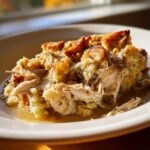A close-up serving of moist crock pot chicken and stuffing with shredded chicken and crispy topping.