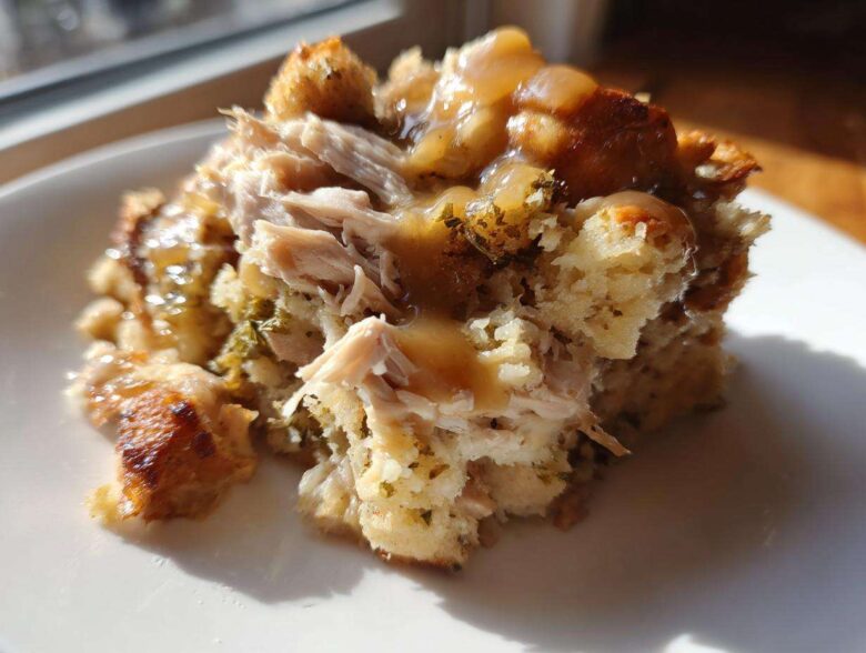 Close-up of a serving of moist crock pot chicken and stuffing topped with savory gravy.
