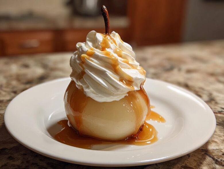 A single, glistening poached pears topped with a swirl of whipped cream and drizzled with caramel sauce on a white plate.