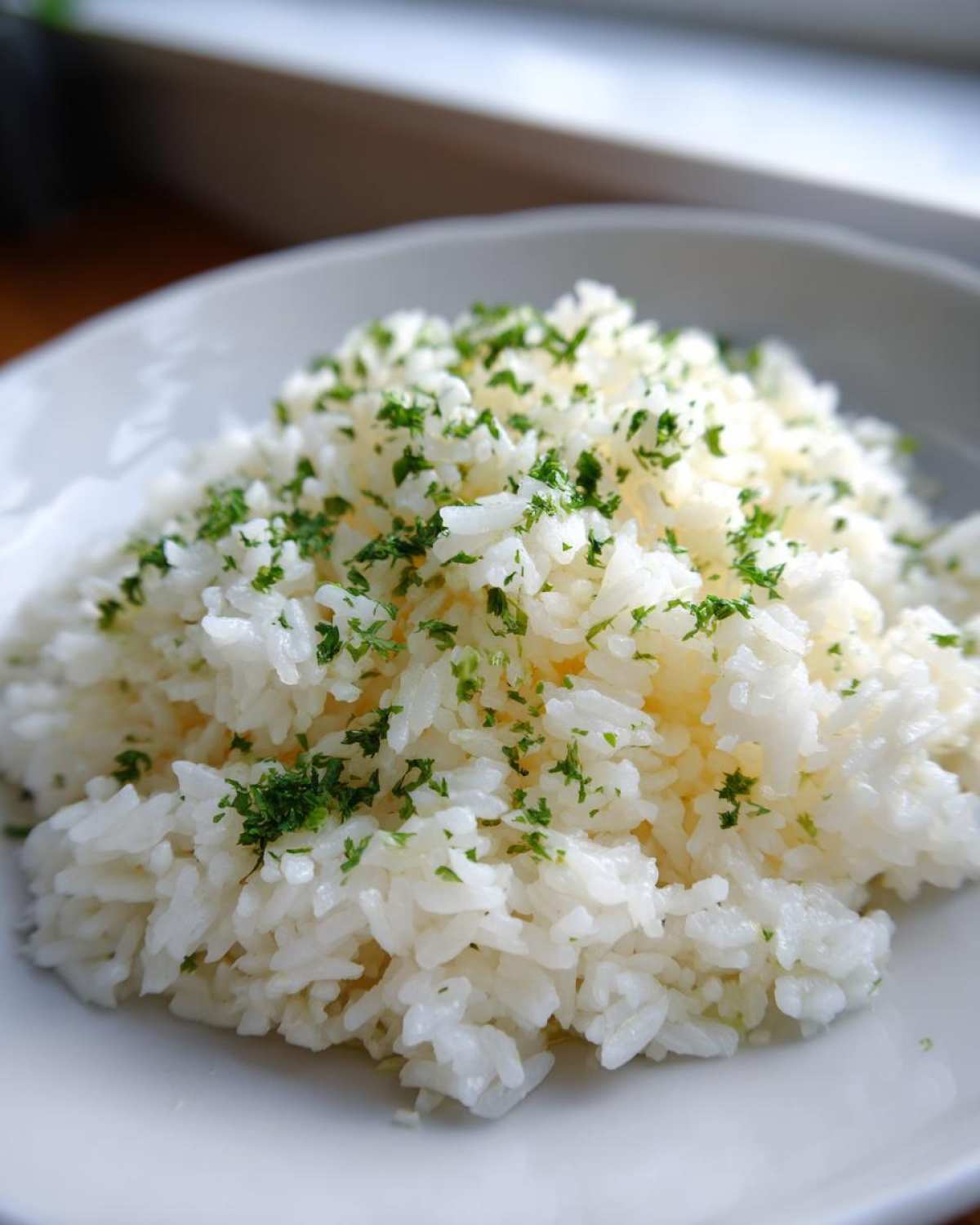 Close-up of fluffy white rice seasoned with butter and topped with chopped green parsley, our easy butter rice recipe.