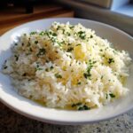 Close-up of fluffy white butter rice seasoned with melted butter, lemon zest, and fresh chopped parsley.