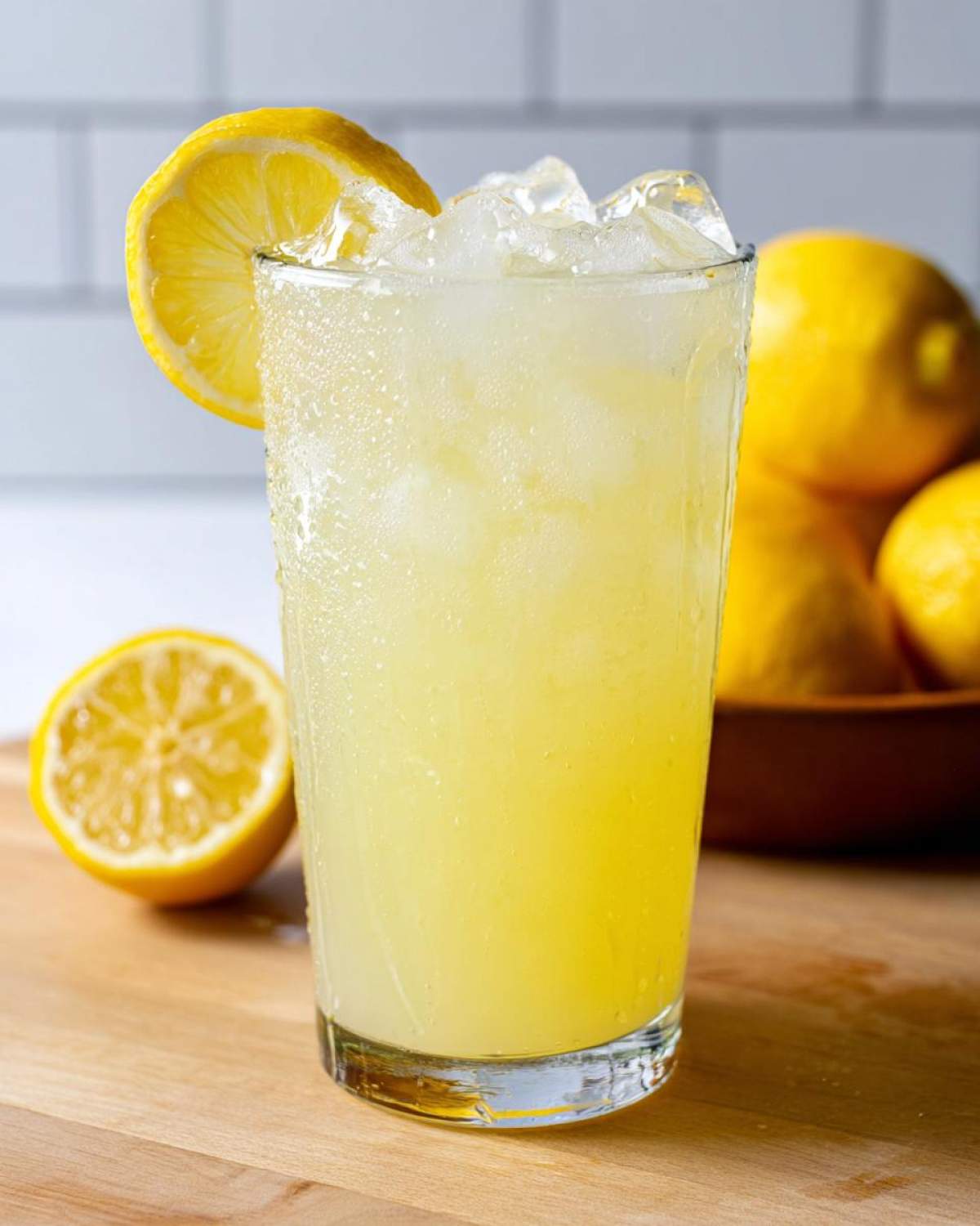 Close-up of a tall glass filled with refreshing homemade lemonade, ice cubes, and a lemon slice garnish.
