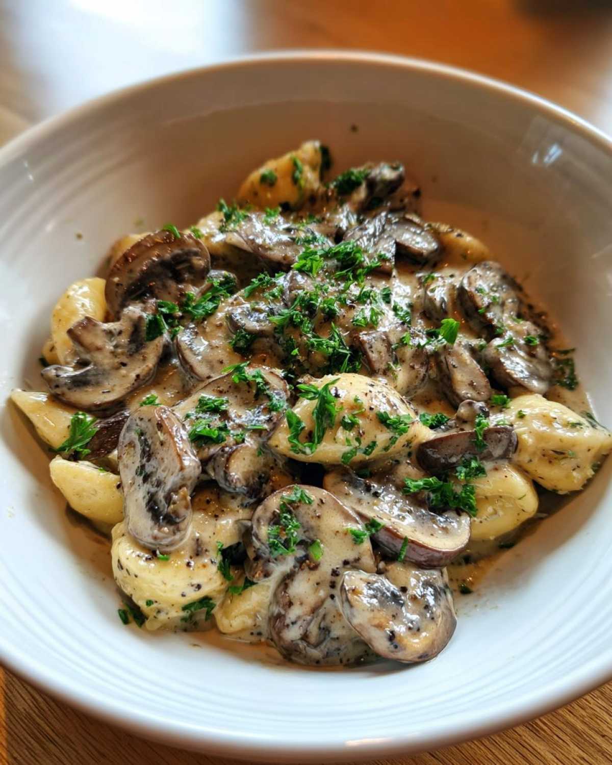 Close-up of gnocchi covered in a rich, creamy mushroom sauce and fresh parsley.