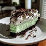 A perfect slice of grasshopper pie with a chocolate crust, mint filling, whipped cream, and chocolate shavings.