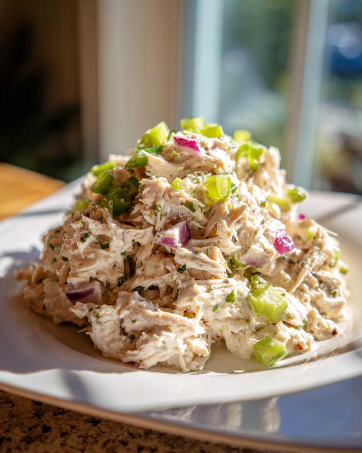 A generous serving of creamy greek yogurt chicken salad topped with diced celery and red onion.