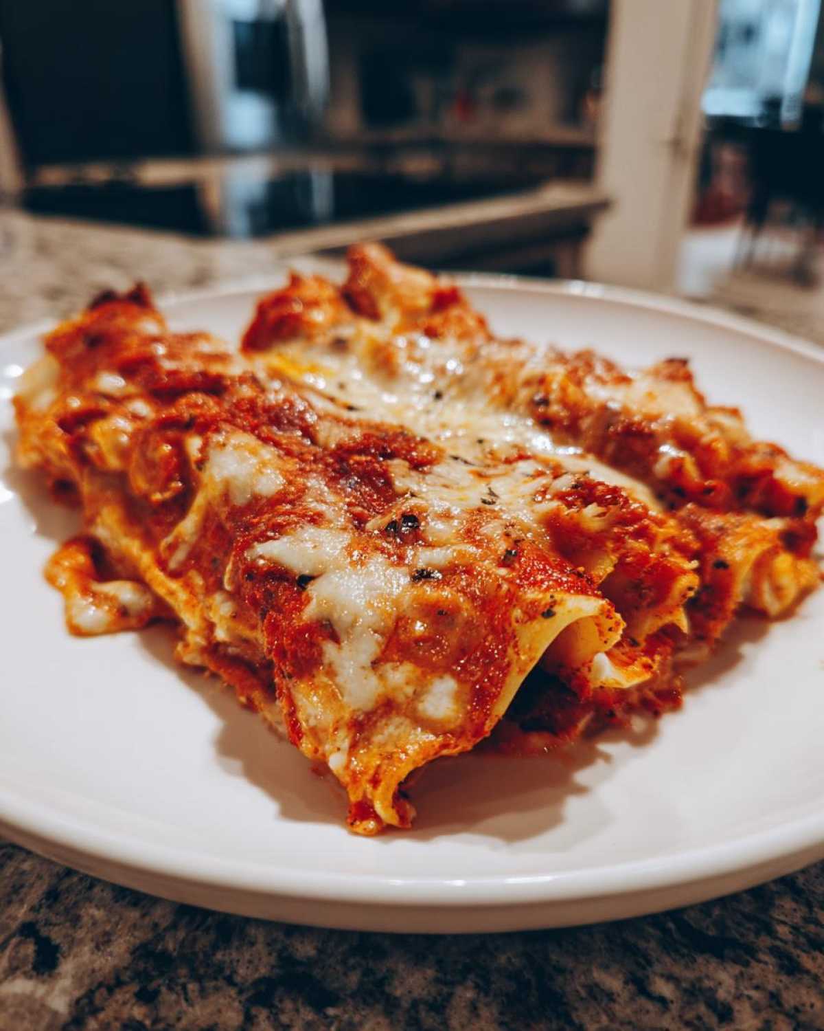 Close-up of rolled cheese enchiladas covered in red sauce and melted, bubbly cheese.