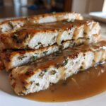 Slices of juicy instant pot turkey breast topped with brown gravy and herbs on a white plate.