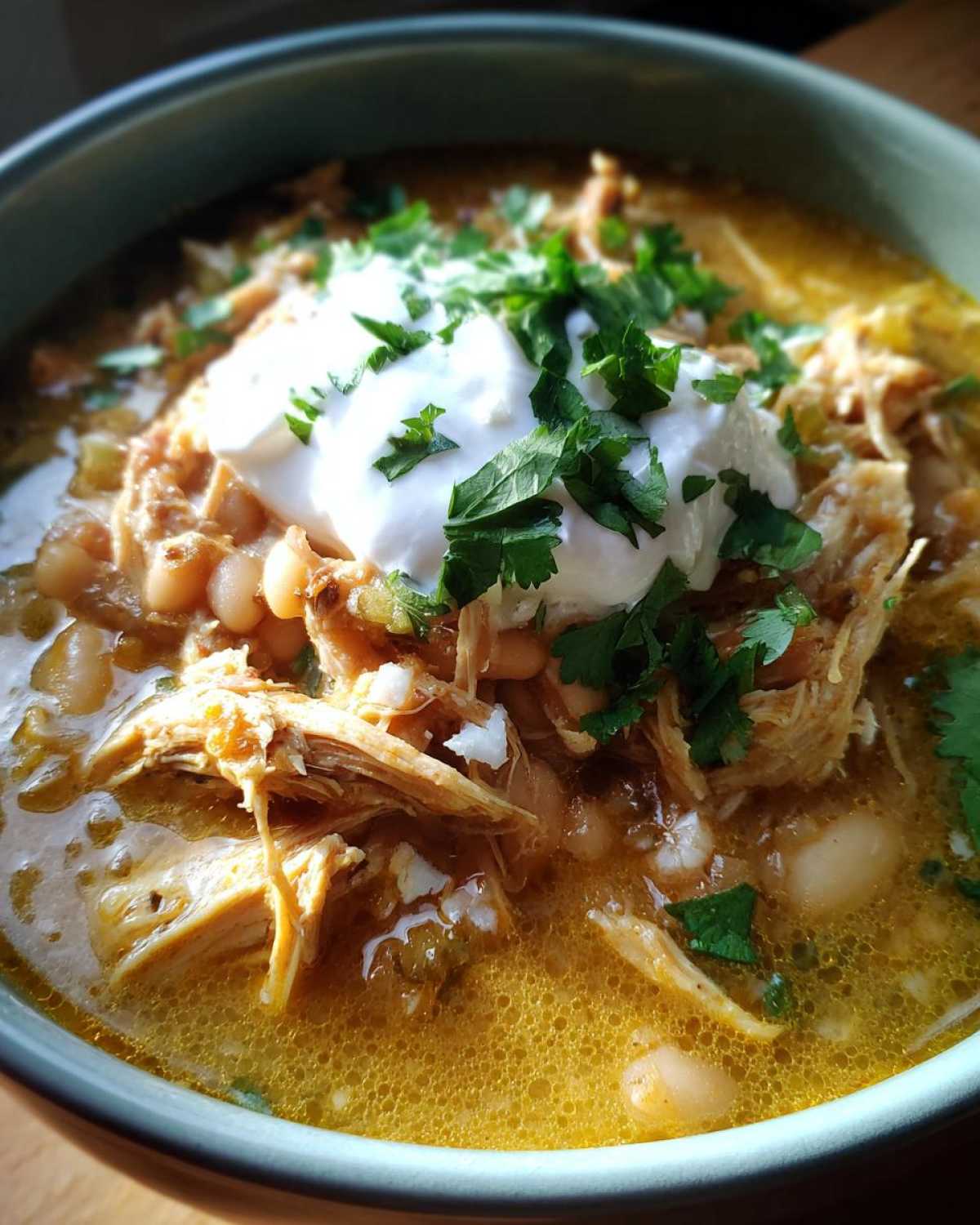 Close-up of a bowl of instant pot white chicken chili topped with sour cream and fresh cilantro.