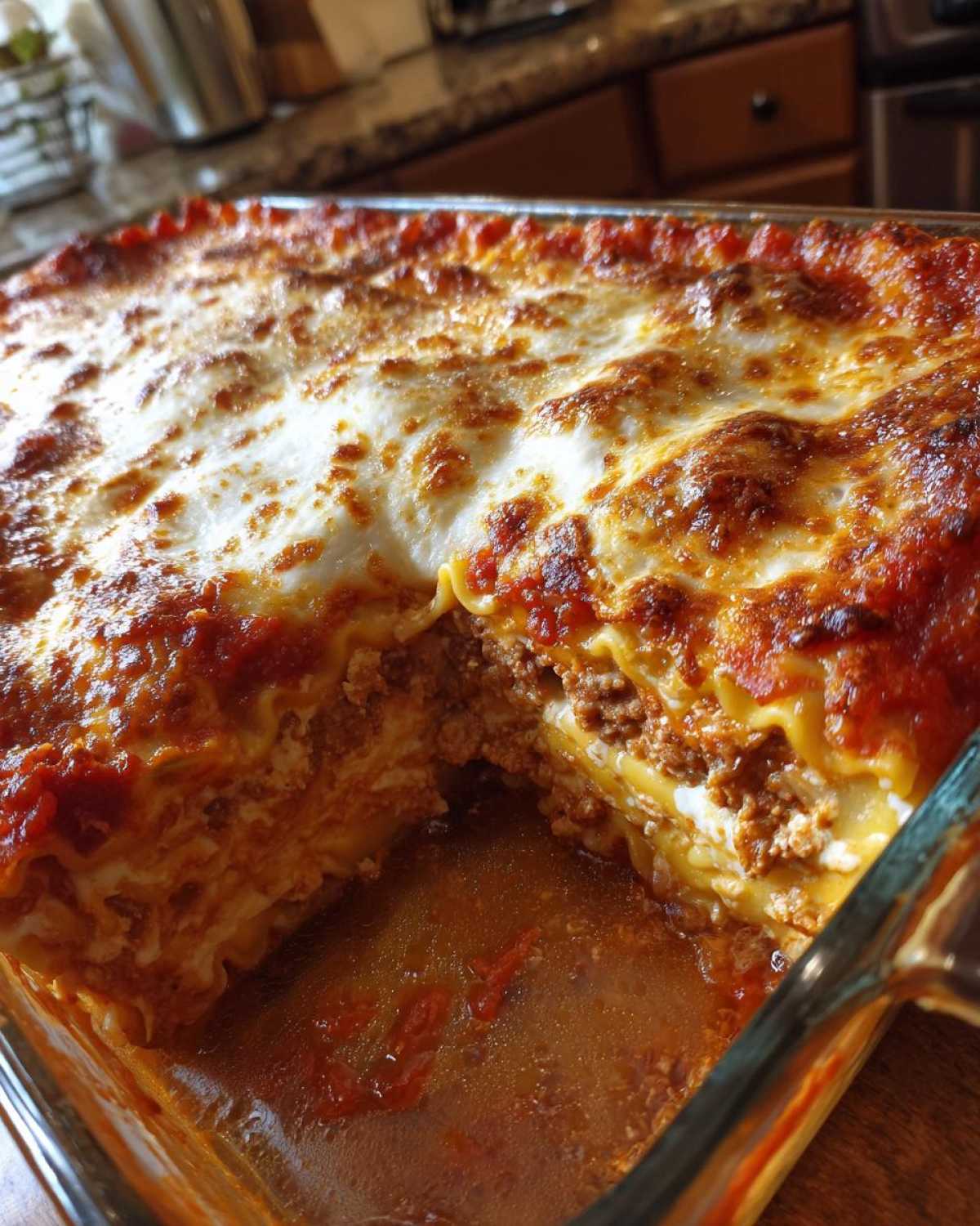 Close-up of a bubbling, cheesy lazy lasagna in a glass baking dish with one serving removed.