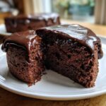 Close-up of a rich, dark slice of flourless chocolate cake oozing with glossy chocolate ganache.