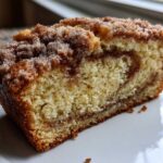 Close-up of a moist slice of snickerdoodle zucchini bread with a cinnamon swirl and crumb topping.