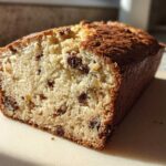 Close-up of a freshly baked slice of vegan banana bread showing a moist crumb and visible chocolate chips.