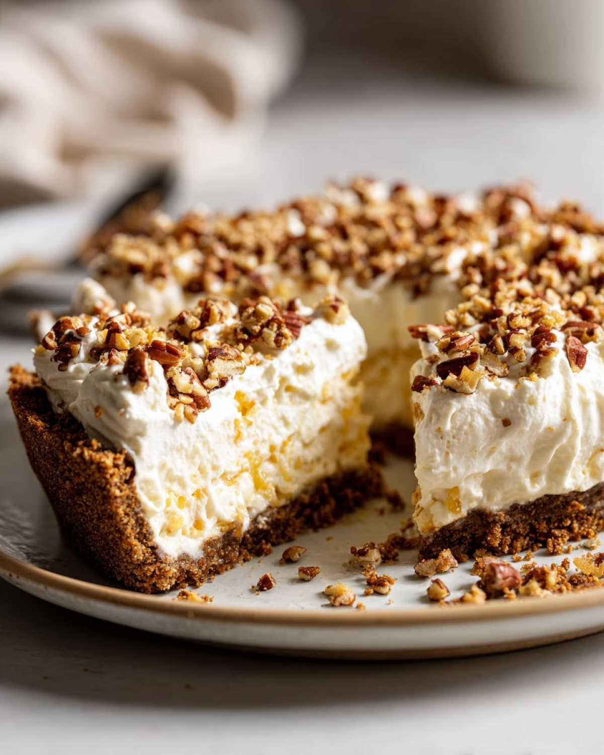 Close-up of a slice removed from a no-bake million dollar pie, topped with whipped cream and chopped pecans.