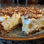 A thick slice of no-bake million dollar pie showing a creamy filling, graham cracker crust, and pecan topping.
