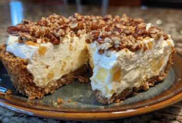 A thick slice of no-bake million dollar pie showing a creamy filling, graham cracker crust, and pecan topping.
