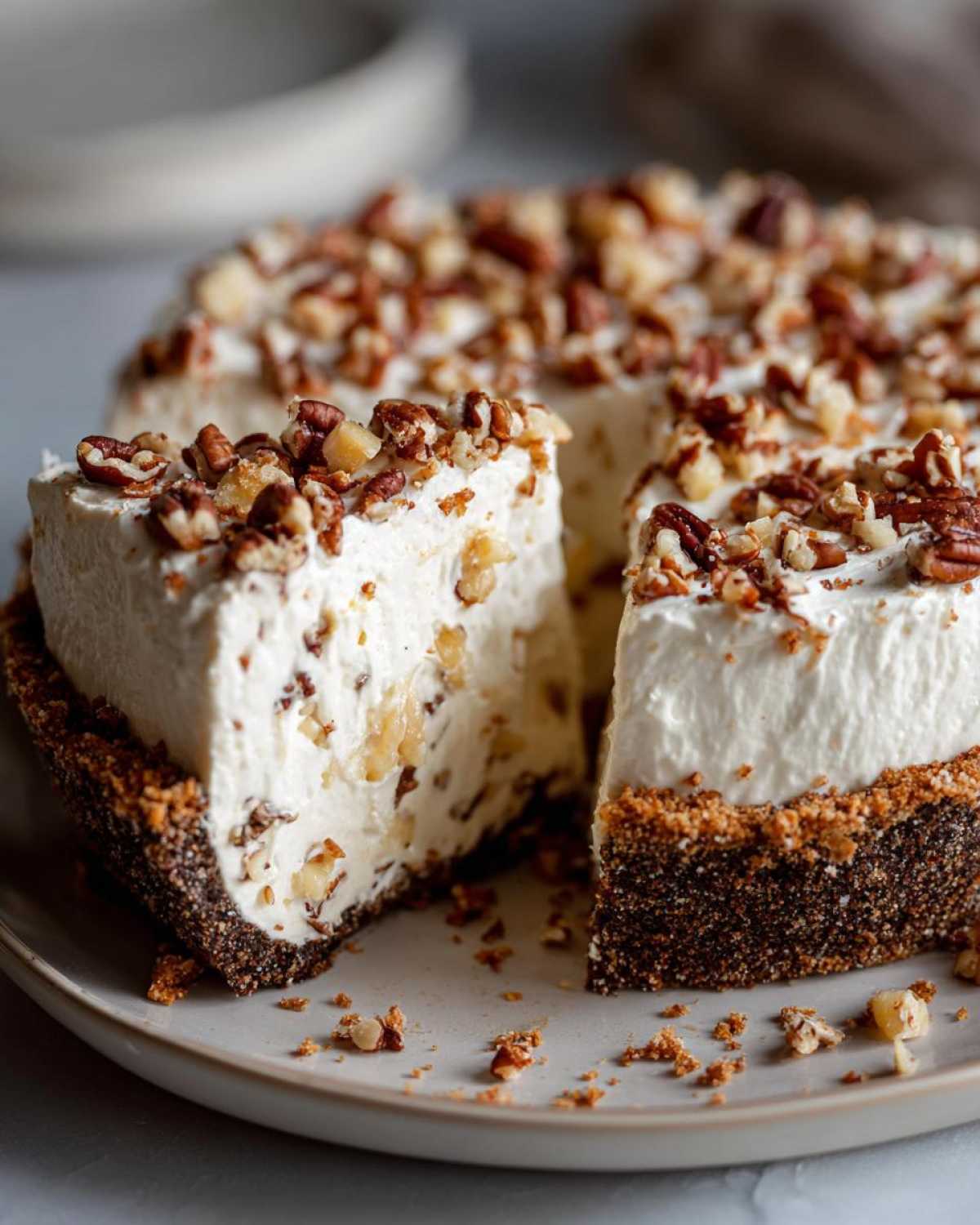 A slice cut from a creamy no-bake million dollar pie topped generously with chopped pecans.