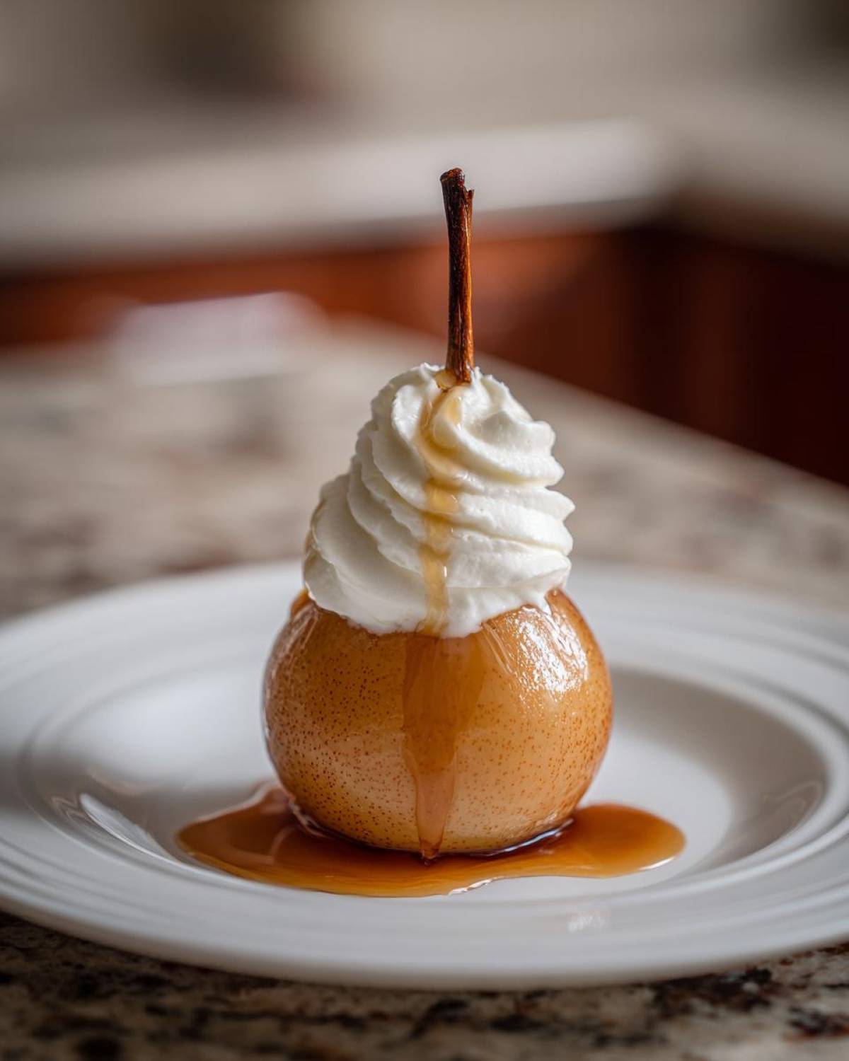 A single, perfectly poached pear topped with whipped cream and drizzled with caramel syrup, resting on a white plate.