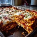A close-up shot of a serving being lifted from a pan of cheesy, saucy lazy lasagna, showing melted mozzarella and meat layers.