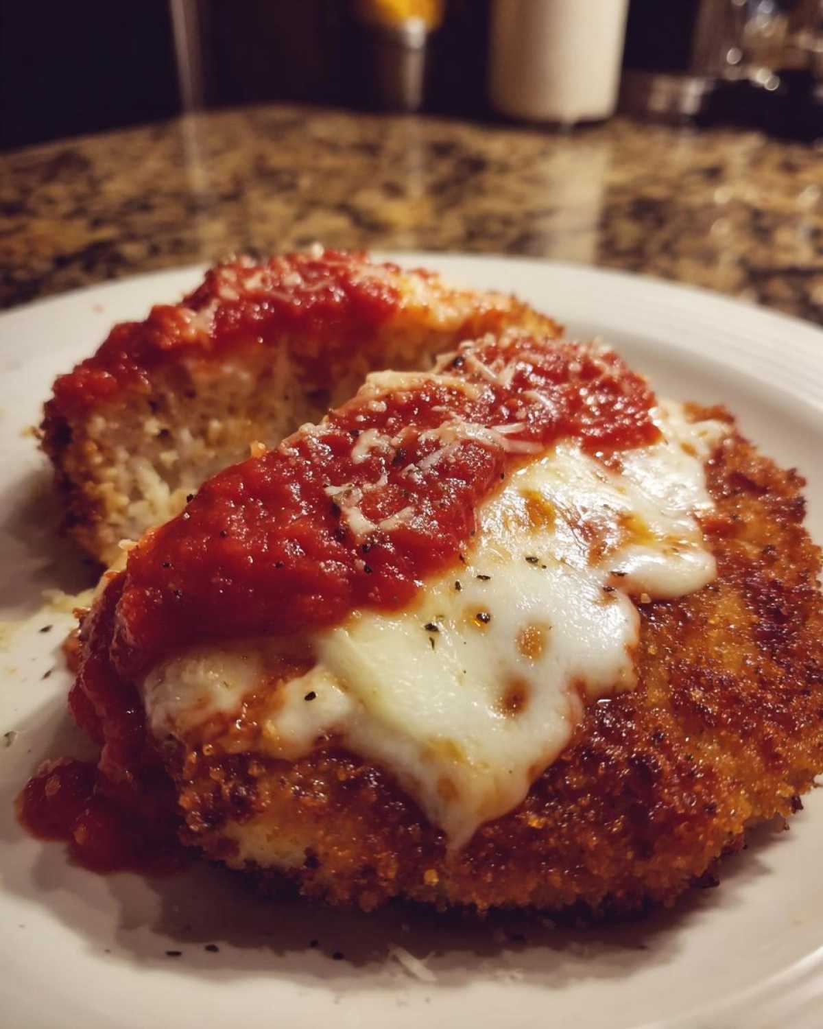 Two pieces of golden brown Air Fryer Chicken Parmesan topped with melted mozzarella and marinara sauce.