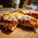 Close-up of a crispy Air Fryer Chicken Parmesan cut open, topped with melted mozzarella and marinara sauce.