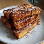 A stack of golden Air Fryer French Toast Sticks generously coated in sparkling cinnamon sugar.
