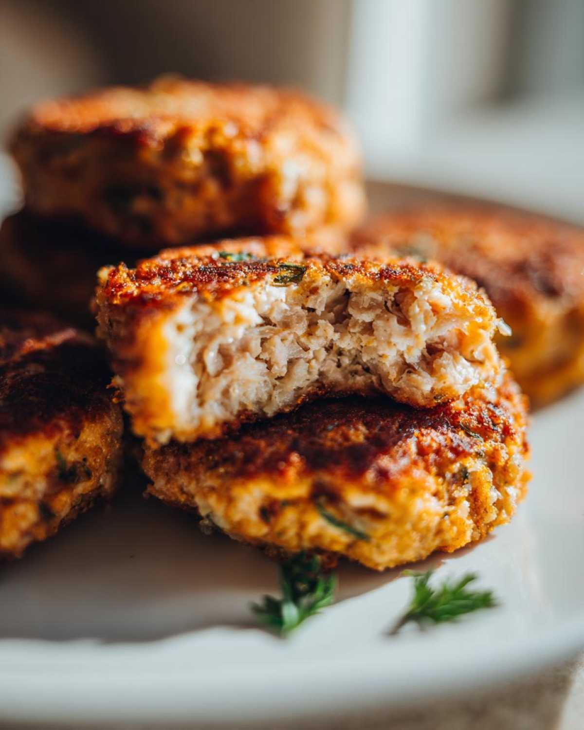 Close-up of Air Fryer Salmon Patties, one broken in half showing the flaky interior and crispy golden-brown exterior.