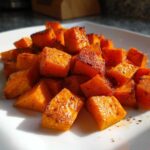 Close-up of seasoned, perfectly crispy Air Fryer Sweet Potato Cubes piled on a white square plate.