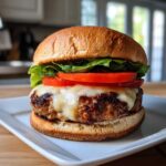 A juicy, fully assembled Air Fryer Turkey Burger topped with melted white cheese, tomato slices, and lettuce on a toasted bun.