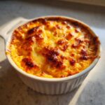 Close-up of hot, bubbly Baked Buffalo Chicken Dip with a golden-brown, cheesy crust in a white ramekin.
