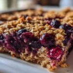 A close-up, macro shot of a rich, moist slice of Blueberry Baked Oatmeal Squares showing the berry filling and oat topping.