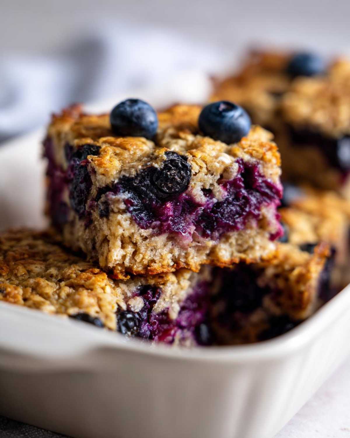 Close-up of stacked Blueberry Baked Oatmeal Squares showing moist interior and fresh blueberries on top.