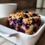 A close-up of a single serving of Blueberry Baked Oatmeal Squares in a white dish.