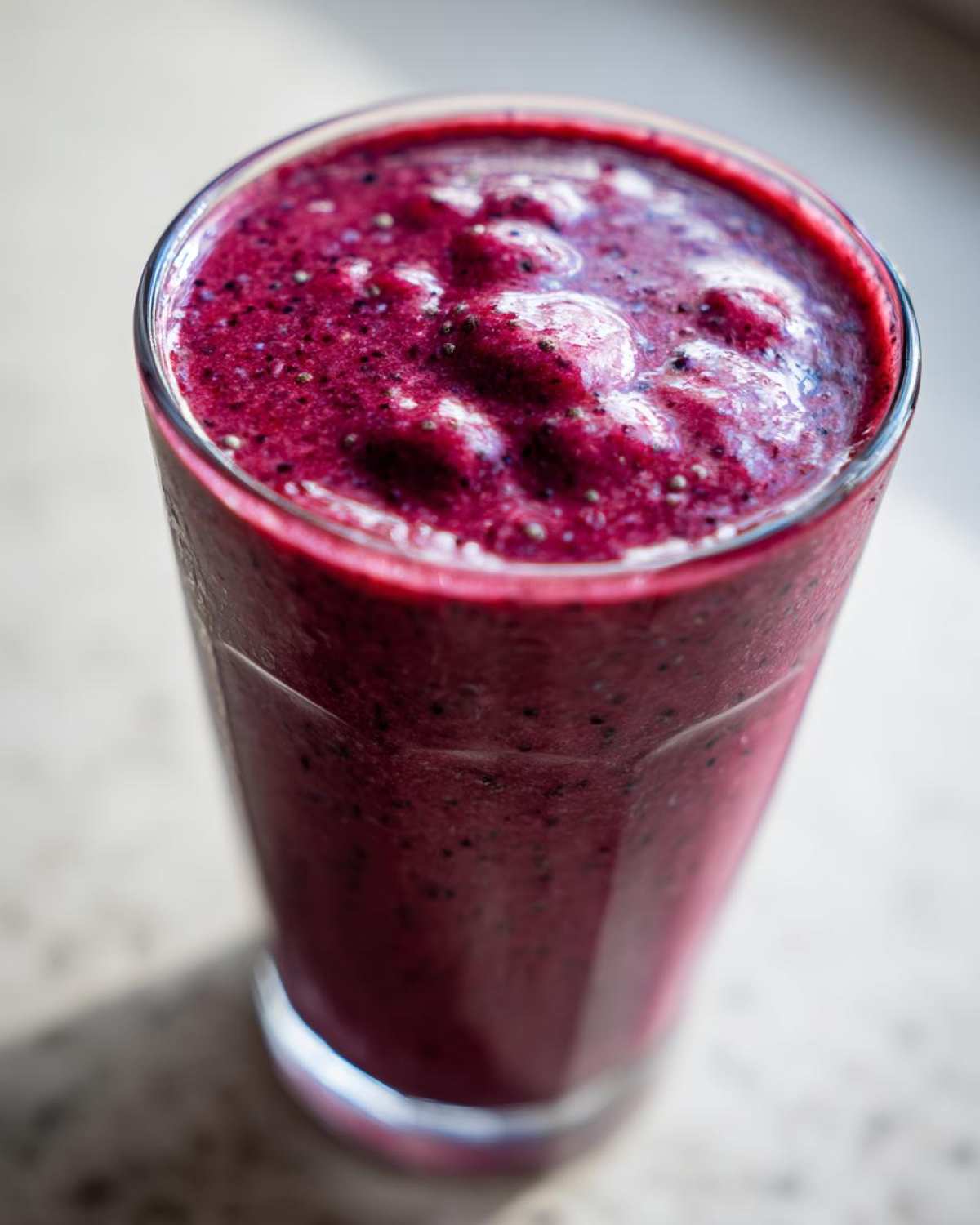 Close-up of a thick, deep purple Blueberry Lemon Chia Smoothie topped with visible chia seeds.