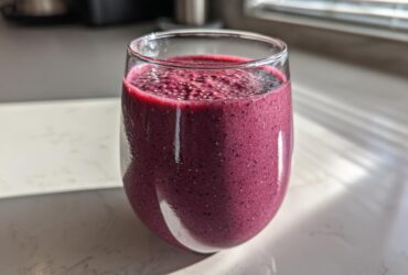 Close-up of a vibrant, deep purple Blueberry Lemon Chia Smoothie topped with visible chia seeds.