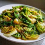 Close-up of vibrant green Cabbage Stir Fry with Garlic Ginger Sauce coating the tender leaves.
