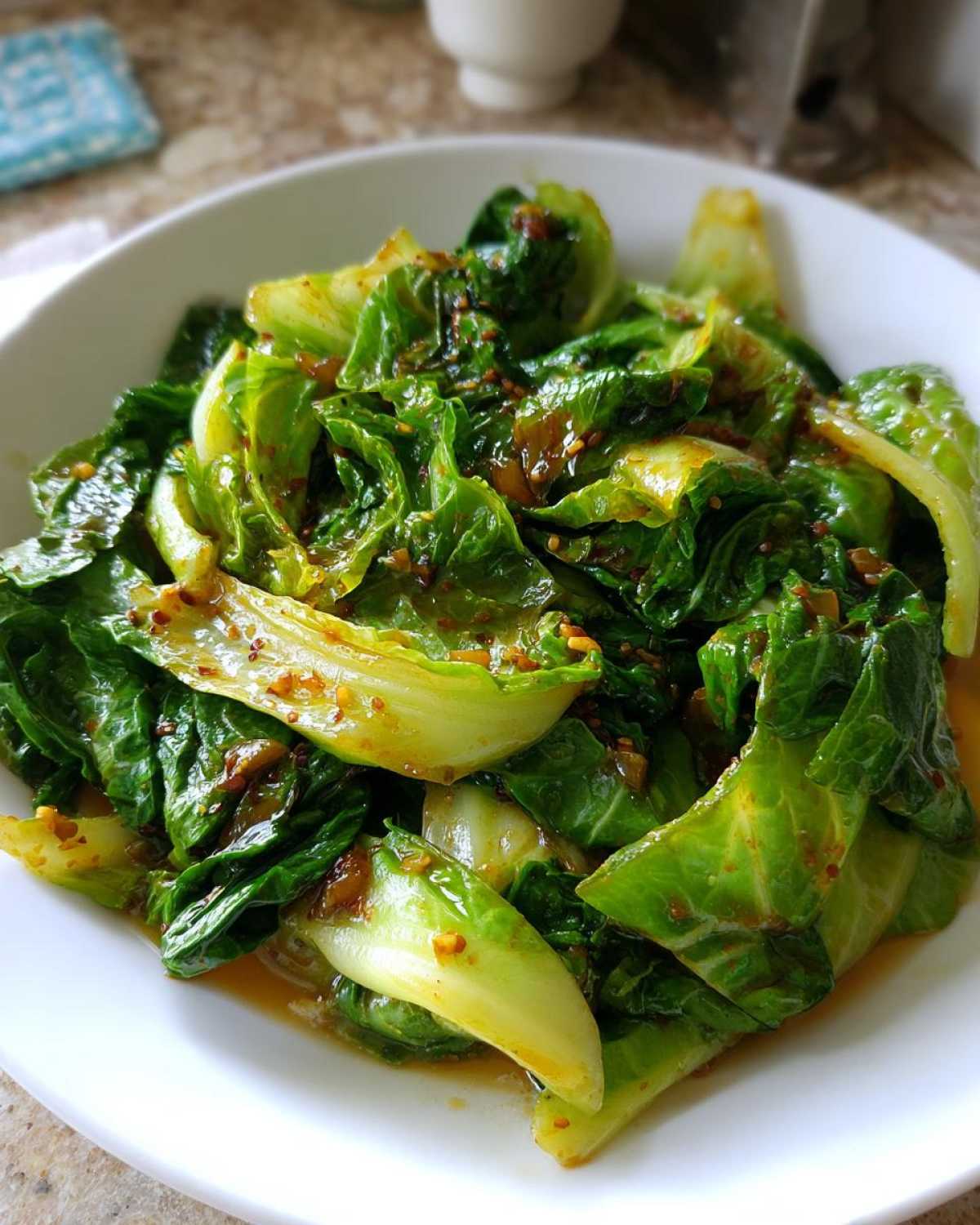 A close-up of bright green Cabbage Stir Fry with Garlic Ginger Sauce served in a white bowl.