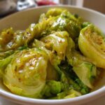 Close-up of glossy, bright green cabbage pieces coated in a savory Garlic Ginger Sauce in a white bowl.