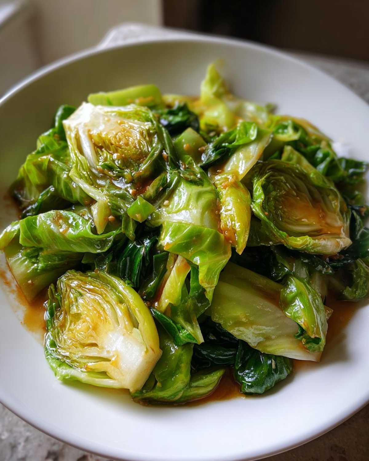 Close-up of vibrant green Cabbage Stir Fry with Garlic Ginger Sauce served in a white bowl.