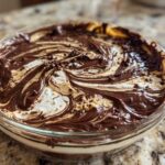 Close-up of Chocolate Peanut Butter Cheesecake Dip swirled with chocolate and peanut butter, topped with sprinkles.
