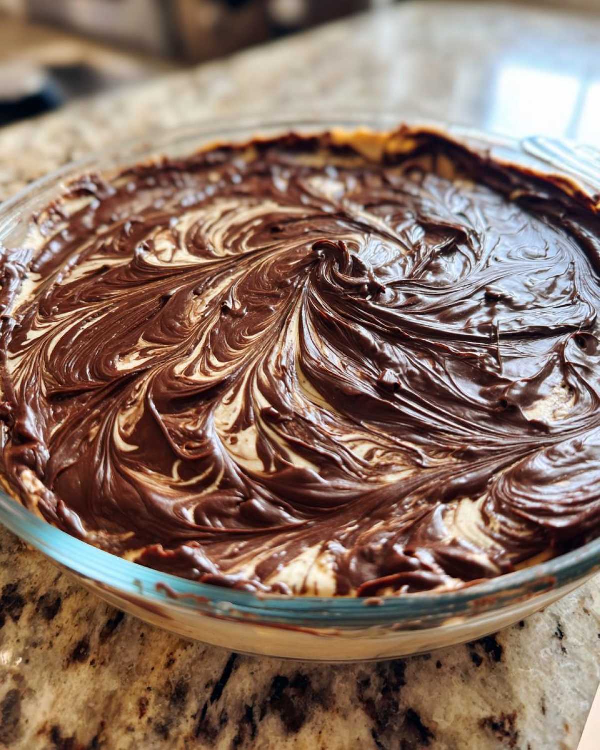 Close-up of Chocolate Peanut Butter Cheesecake Dip with swirled chocolate topping in a clear glass dish.