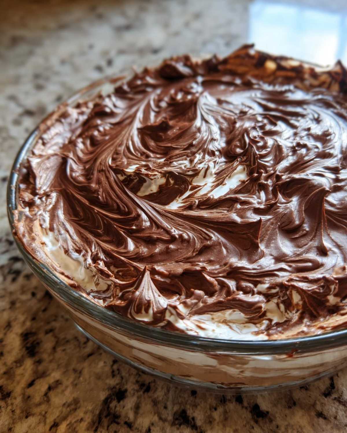 Close-up of Chocolate Peanut Butter Cheesecake Dip with swirled chocolate topping in a glass bowl.