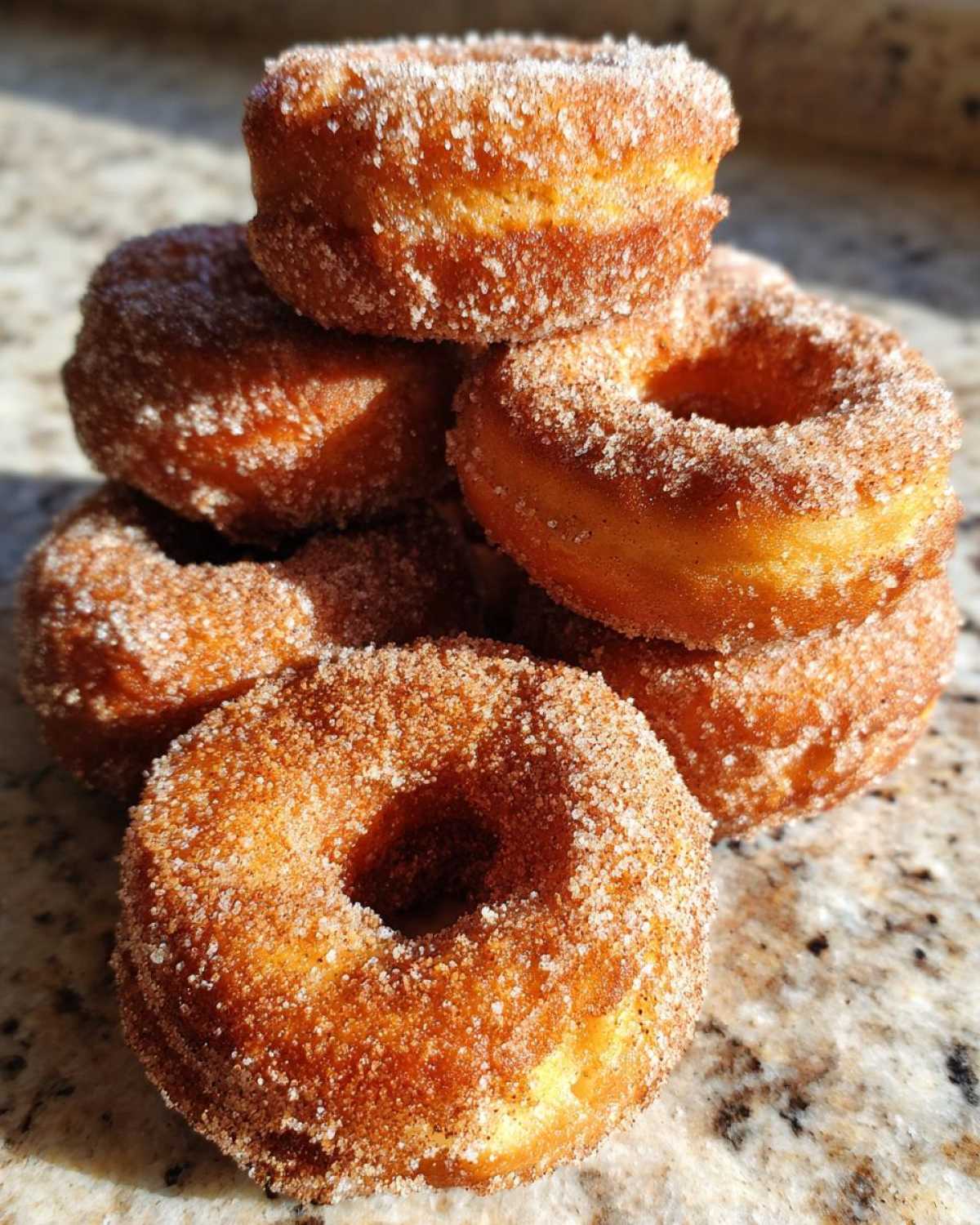 A tempting stack of golden Cinnamon Sugar Air Fryer Donuts heavily coated in sparkling cinnamon sugar.