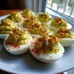 A plate of perfectly prepared Classic Deviled Eggs with Dill Pickle Relish, topped with paprika and fresh dill.