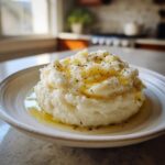 A mound of fluffy Creamy Garlic Mashed Cauliflower drizzled with melted butter or olive oil and topped with cracked black pepper.